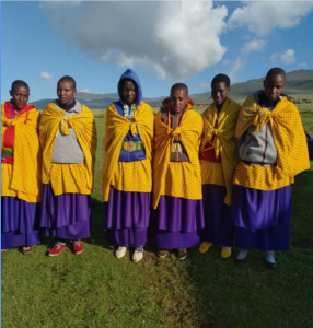 Six special Maasai ladies wearing special shukas for a special occasion: Student Celebration. These are Maasai Harmonial's two medical interpreters (left) and four craft leaders (right)